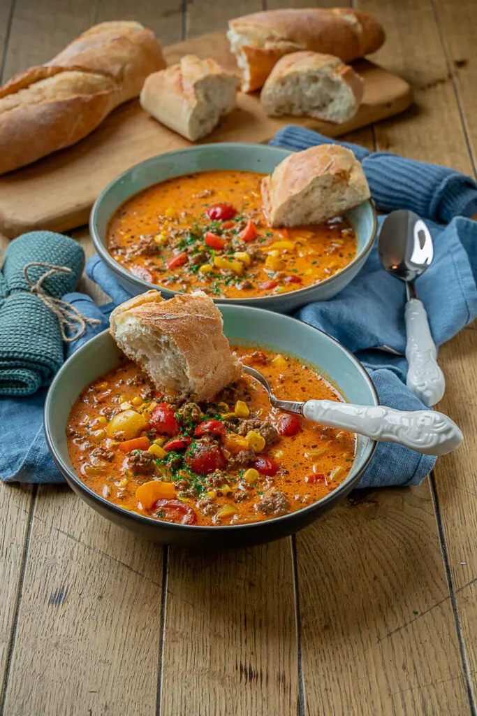 Eine Schüssel dampfender Pizzasuppe mit Käse bestreut und frischem Brot, perfekt für ein schnelles Abendessen.