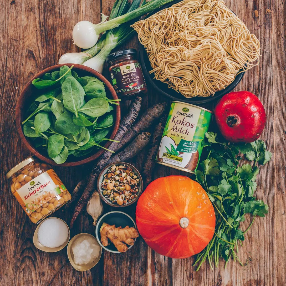 Eine Schüssel Kürbis-Curry mit Mie-Nudeln, garniert mit frischem Koriander und Granatapfelkernen.