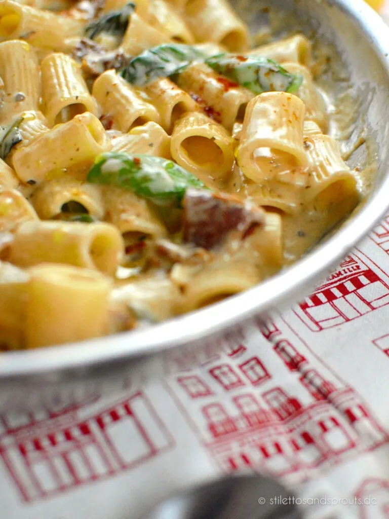 Eine Schüssel mit Marry Me Pasta, garniert mit frischem Basilikum und geriebenem Parmesan, auf einem rustikalen Holztisch