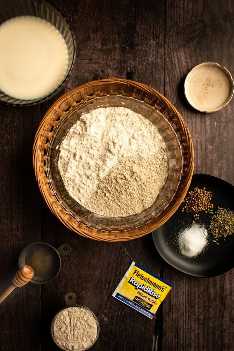 Eine Schüssel mit Roggenmehl in einem Korb neben Zutaten für einen Brotlaib.