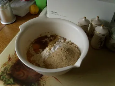 Eine Schüssel mit Zutaten für Lebkuchen, darunter Mehl, Zucker, Honig und Gewürze, die zu einem Teig vermischt werden.