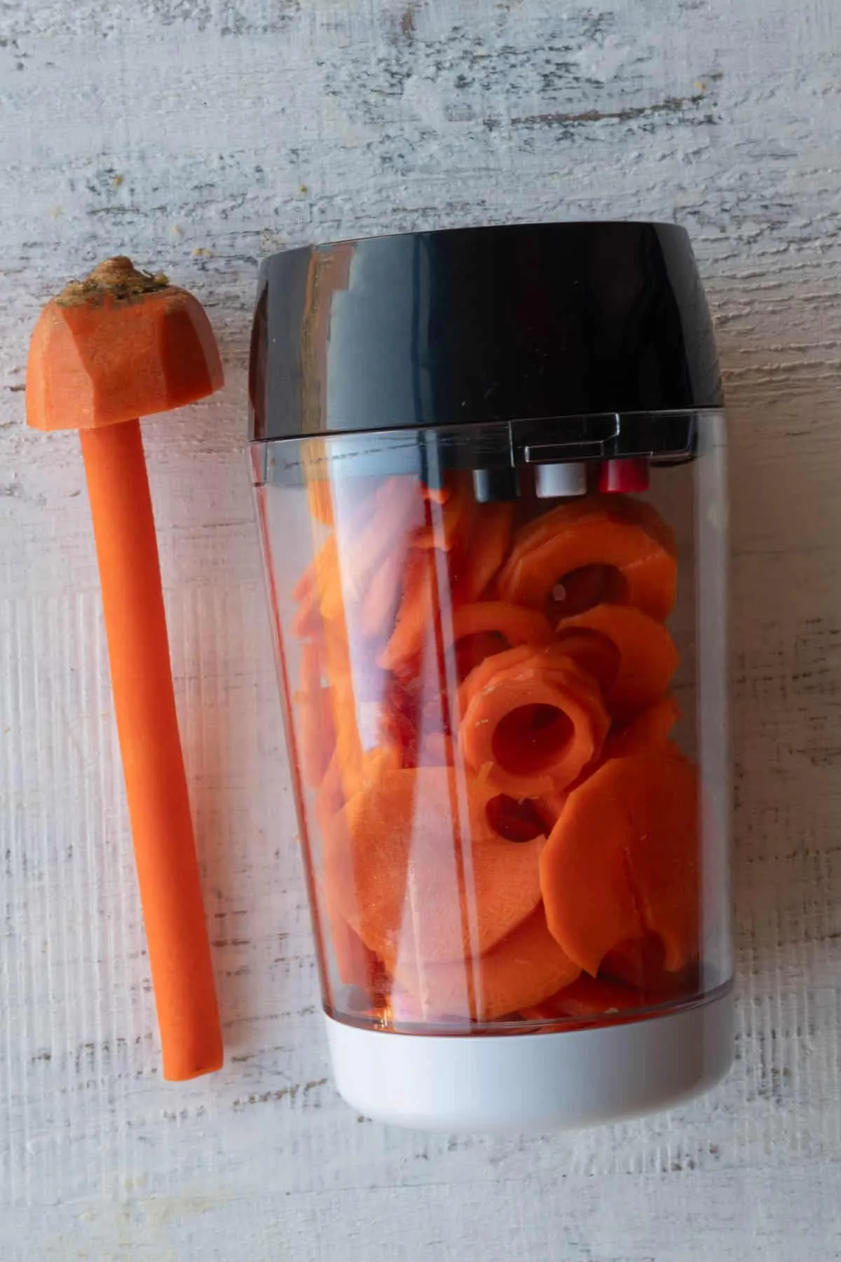 Eine spiralförmig geschnittene Karotte neben dem Gemüsespiralizer, bereit für den Wrap-Salat.