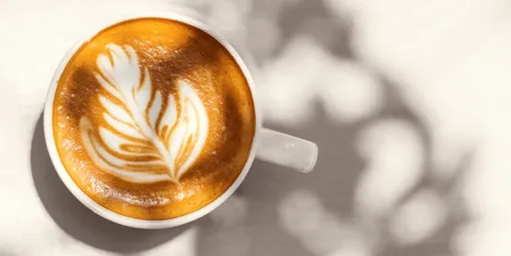 Eine Tasse Cappuccino mit Latte Art auf weißem Hintergrund