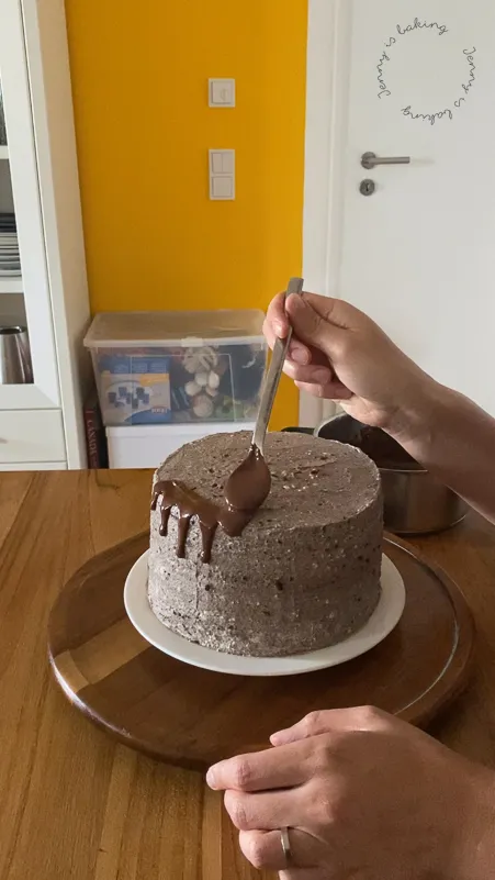 Eine Torte erhält einen Schoko-Drip als Dekoration, nachdem sie perfekt glatt eingestrichen wurde.