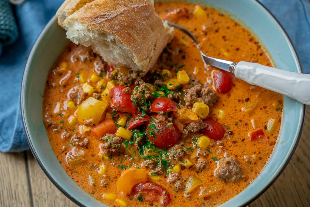 Eine warme, cremige Pizzasuppe mit sichtbaren Hackfleisch- und Gemüsestücken, bereit zum Genießen.