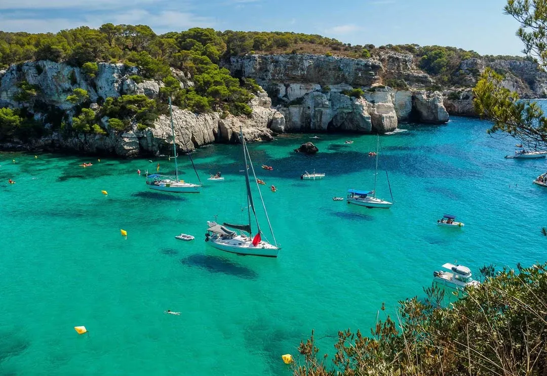 Eine wunderschöne Bucht auf Menorca, umgeben von Felsen und klarem Mittelmeerwasser.