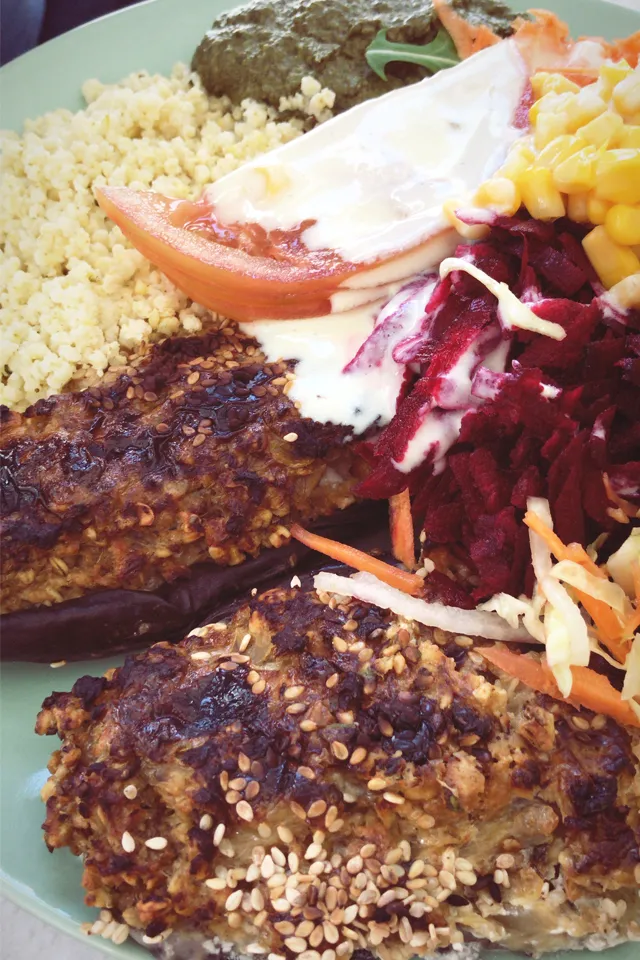 Eine Zusammenstellung verschiedener veganer Tagesgerichte, darunter Salat, Couscous und gefüllte Auberginen