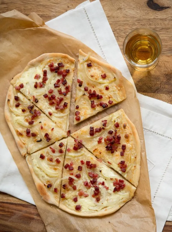 Einfaches Rezept für Flammkuchen: eine halbe Flammkuchen-Portion auf einem Holzbrett