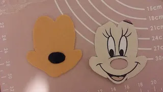 Einzelne Fondant-Elemente wie Augen und Nase für das Minnie Maus Gesicht, bereit zum Zusammenfügen auf dem Geburtstagskuchen.
