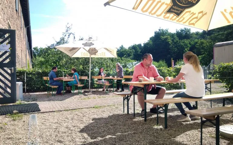 Entspannter Biergarten des Café Kranich im Jagdschloss Kranichstein mit Holztischen und Sonnenschirmen