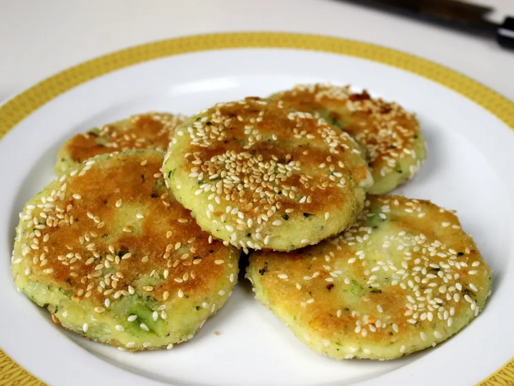 Erdäpfel-Karfiol-Laibchen auf einem Teller mit frischem Salat, perfekt für glutenfreie Rezepte mit Karfiol