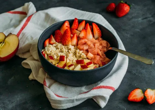 Erdbeer-Rhabarber-Porridge in einer Schale mit frischen Erdbeeren und Rhabarber.