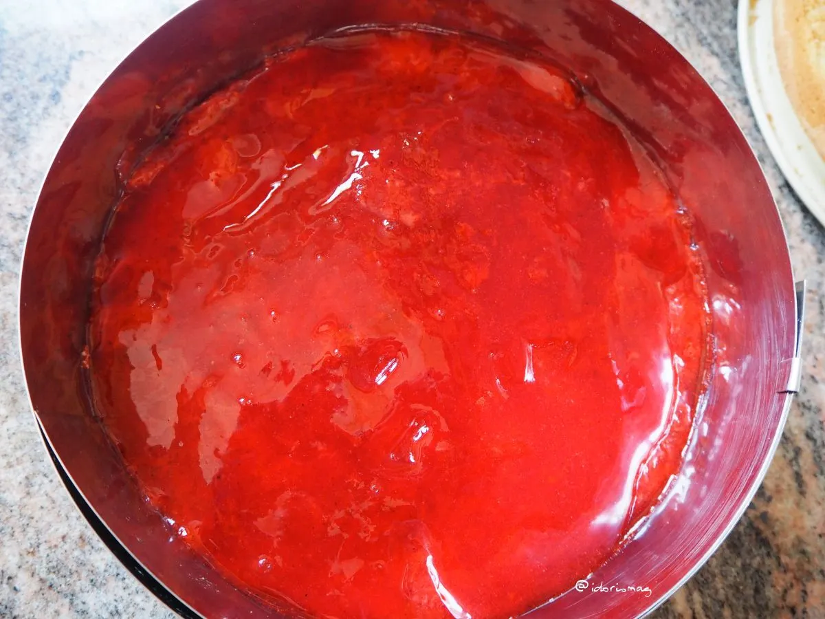 Erdbeermarmelade auf dem gebackenen Biskuitboden in einem Tortenring