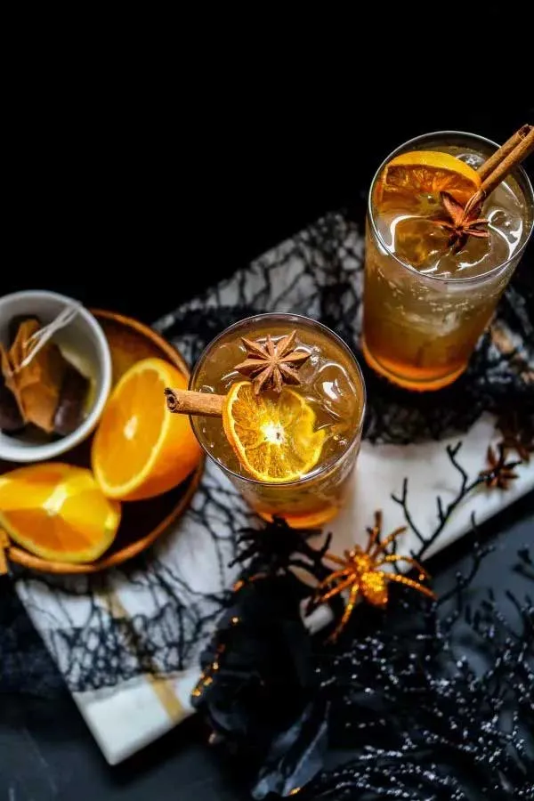 Erfrischender Gewürz-Vanille-Chai-Eistee-Mocktail mit Orangenscheiben und Zimtstangen
