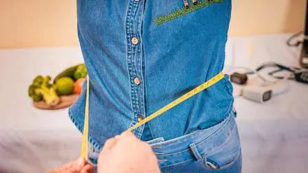 Ernährungsberater misst den Taillenumfang einer Patientin, im Kontext von schnellem Abnehmen und den Risiken von Crash-Diäten.