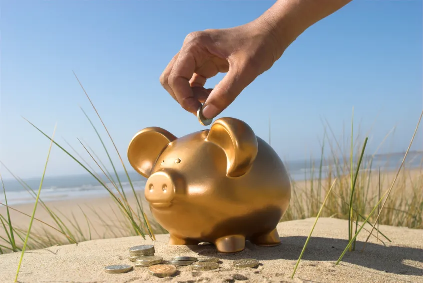 Euro-Schein im Sandstrand als Symbol für unschlagbare Reise-Schnäppchen und billige Angebote