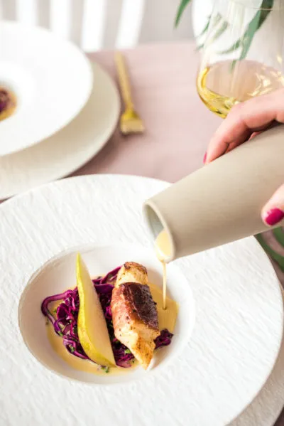 Exquisit angerichtetes Skrei Gericht mit Birnenspalten auf rustikalem Geschirr