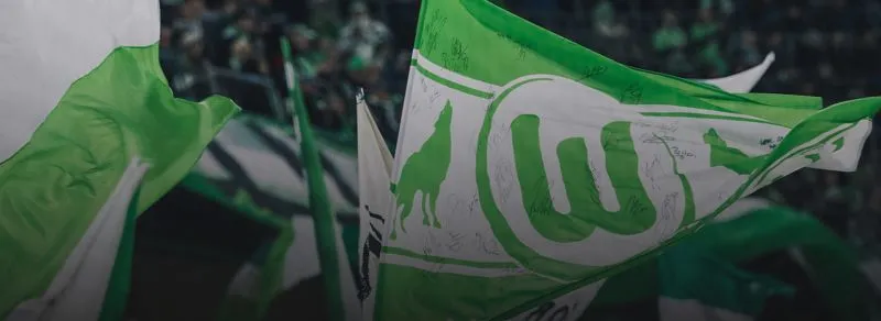 Fans schwingen ihre grün-weißen Fahnen und feiern die Atmosphäre eines Bundesligaspiels.