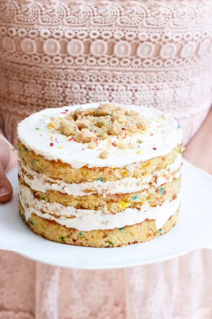 Farbenfroher Funfetti Schichtkuchen auf einem Kuchenständer mit Streuseln und cremigem Frosting