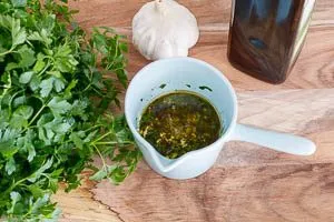 Fein gehackte Petersilie und Knoblauch werden mit Olivenöl, Meersalz und Pfeffer für das Spargelgericht vermischt.