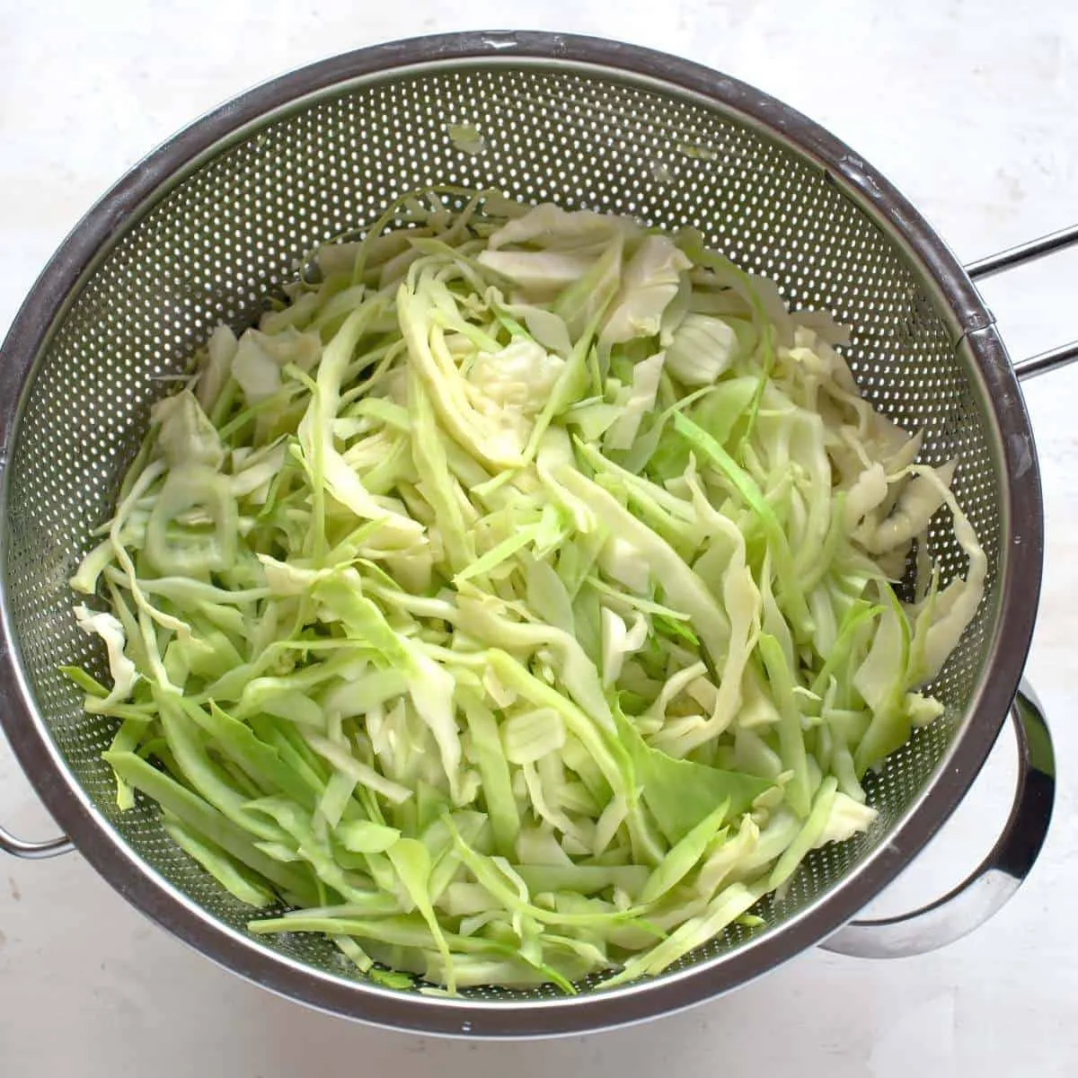 Fein geschnittener grüner Kohl in einem Sieb.