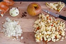 Fein gewürfelte Äpfel und Zwiebeln sowie eine mit Nelken gespickte Zwiebel für die Rotkraut Zubereitung