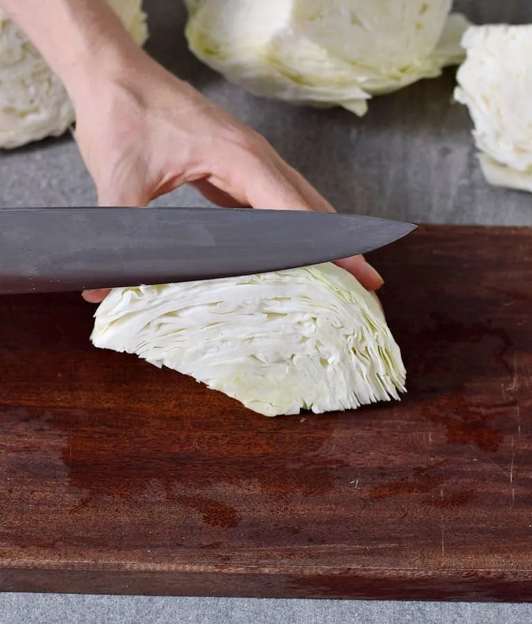 Feines Schneiden von Weißkohl mit einem großen Messer auf einem Holzbrett, ein wichtiger Schritt beim Sauerkraut selber machen.