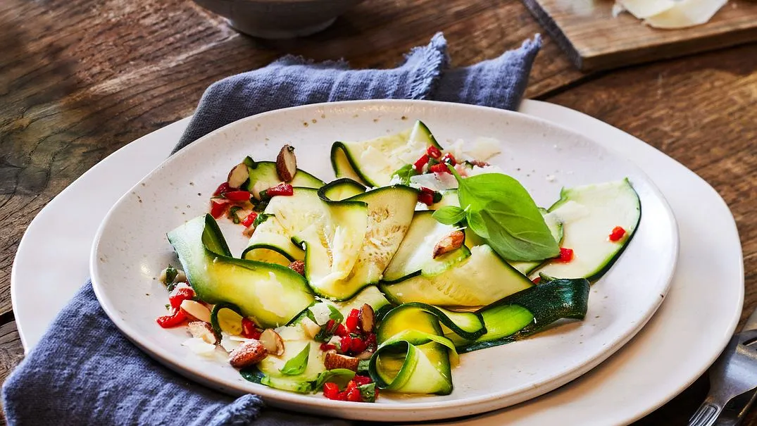 Feines Zucchini-Carpaccio garniert mit Mandeln und Parmesan, ein leichtes vegetarisches Sommergericht