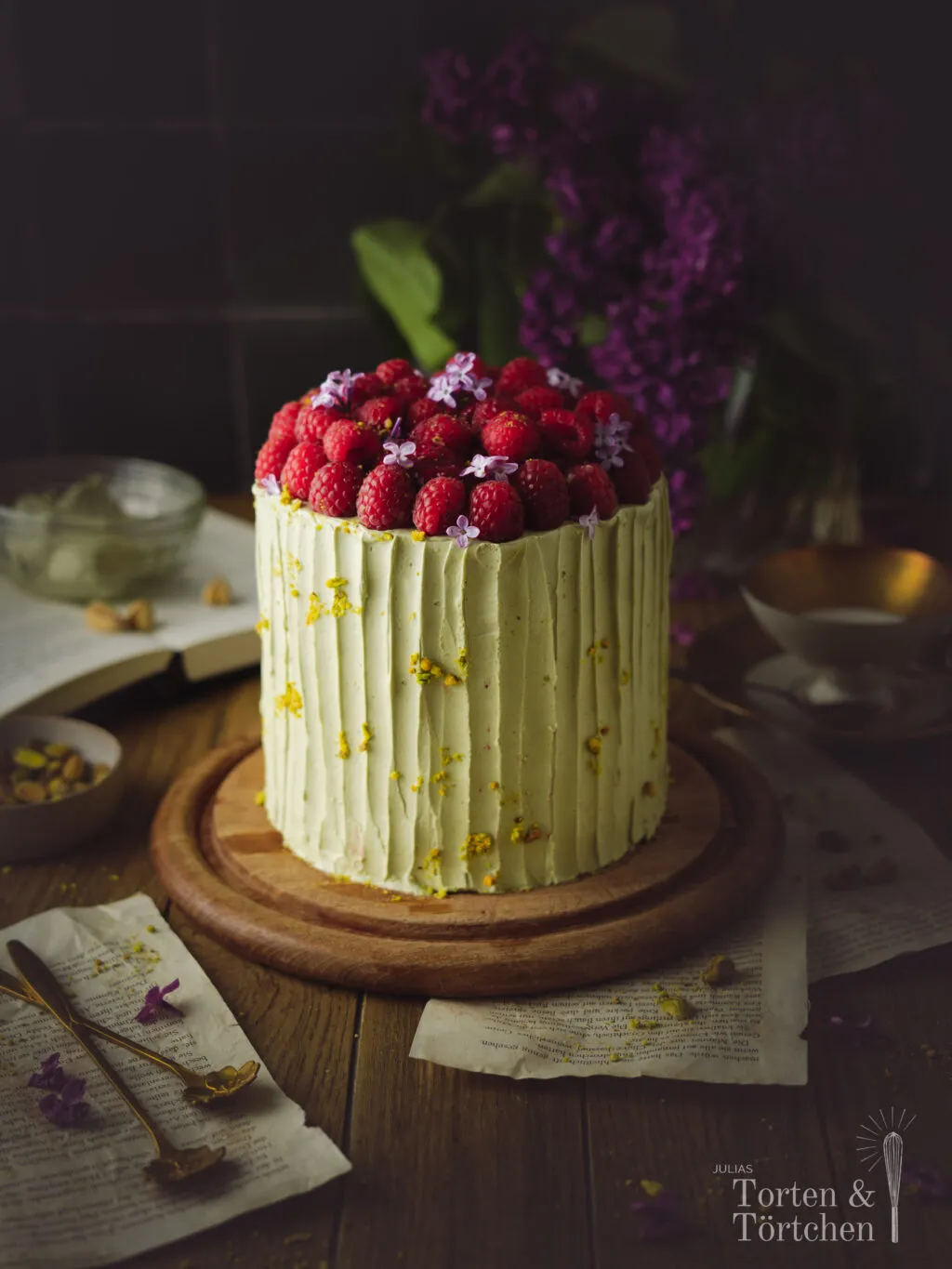 Fertig dekorierte Pistazien Himbeer Torte mit frischen Früchten und Blumen