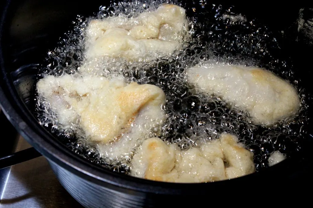 Fertig frittierte Egli Filets im Bierteig werden auf Küchenpapier abgetropft, um überschüssiges Öl zu entfernen