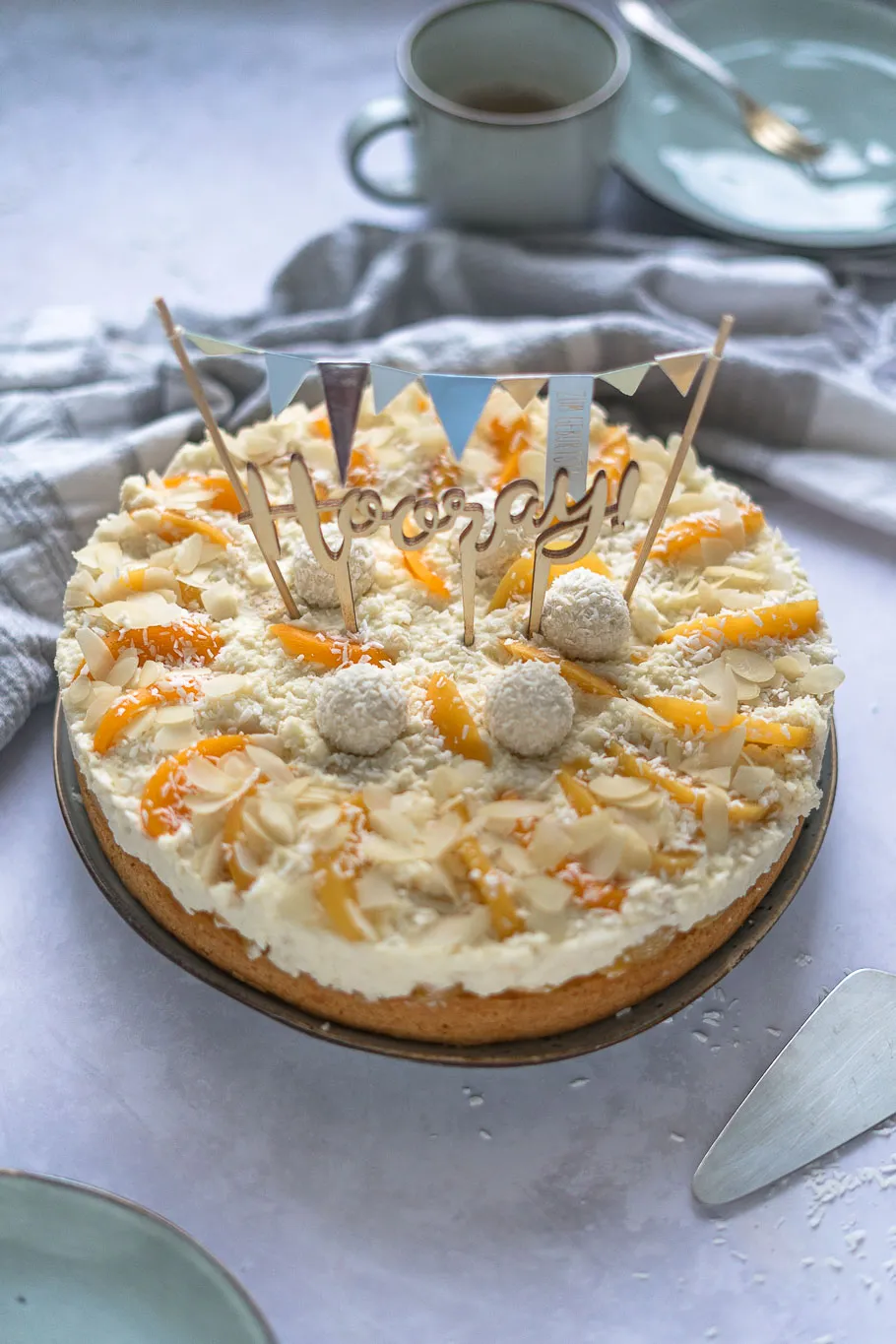 Fertig gebackene Pfirsich-Maracuja-Raffaelo-Torte mit frischen Pfirsichspalten und Raffaello-Kugeln dekoriert