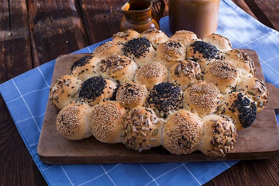 Fertig gebackene Wagenrad Brötchen als appetitliche Brötchensonne angerichtet, umgeben von verschiedenen Dips für ein deutsches Buffet.