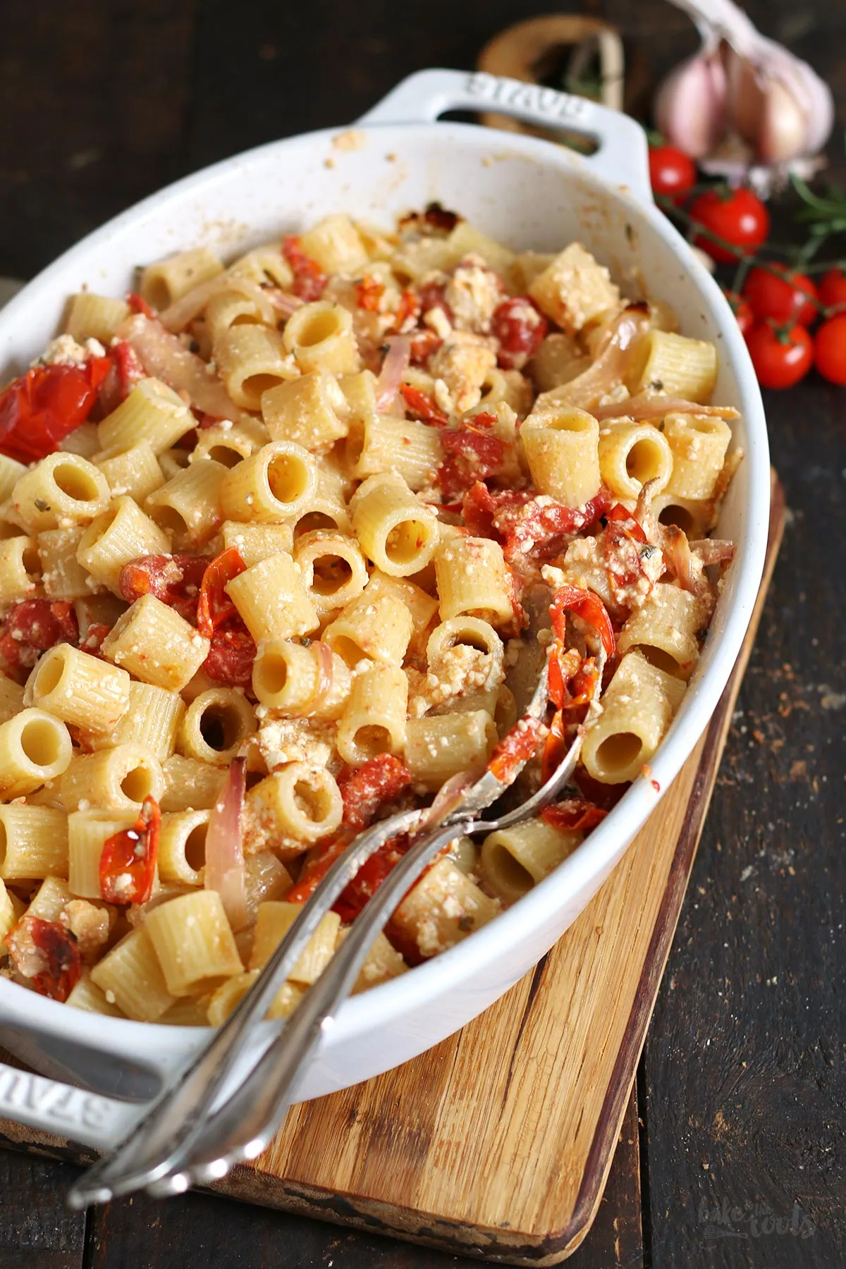 Fertig gebackener Feta und weiche Tomaten in der Auflaufform, bereit zum Vermischen