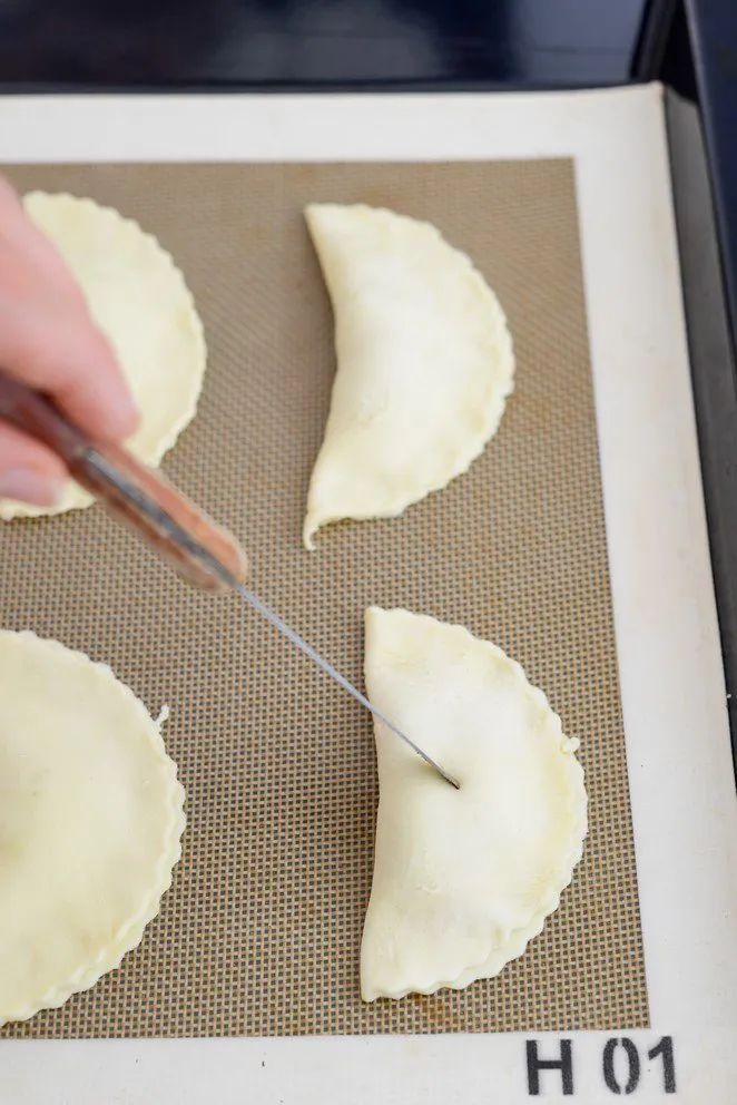 Fertig geformte Mirabellentaschen mit kleinen Einstichen auf dem Backblech