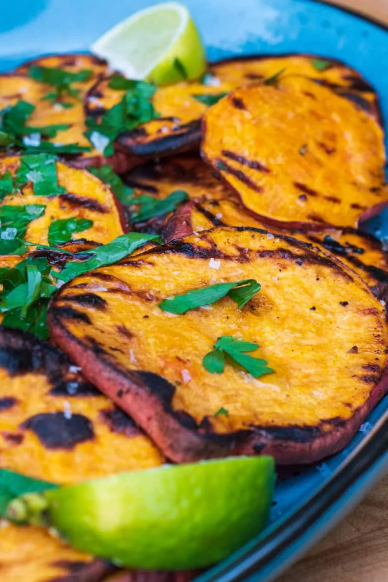Fertig gegrillte Süßkartoffelscheiben, ansprechend angerichtet und mit frischer Petersilie garniert, servierbereit.