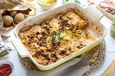 Fertig geschichteter Hackfleisch-Kartoffel-Auflauf mit geriebenem Käse vor dem Backen