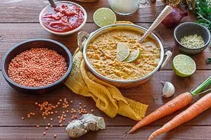 Fertig zubereitete rote Linsensuppe mit Kokosmilch in einer Schale, garniert mit frischen Kräutern, bereit zum sofortigen Servieren und Genießen.
