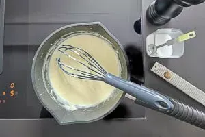 Fertige Béchamelsauce wird mit Gewürzen wie Salz, Pfeffer und Muskatnuss verfeinert und abgeschmeckt