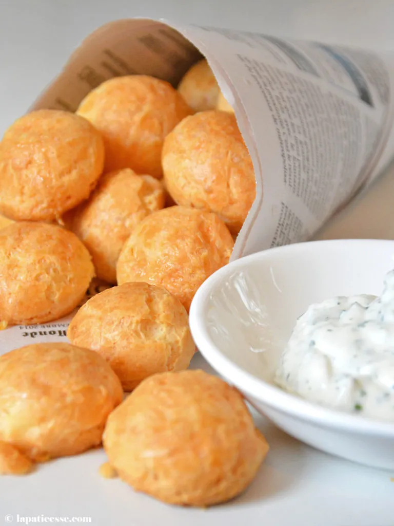Fertige goldbraune Brandteig Käsewindbeutel mit Gruyère Käse, servierfertig auf einem Teller angerichtet. Ideal für Ihr Brandteig Rezept.