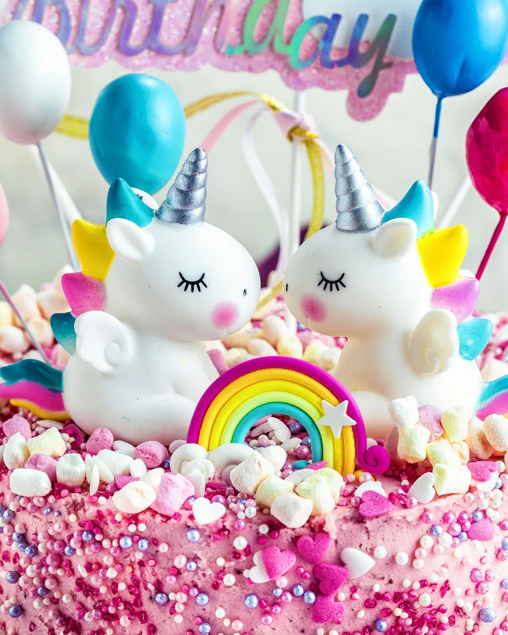 Fertige rosa Einhorn-Torte mit bunten Streuseln und Einhornfiguren, perfekt für einen Kindergeburtstag