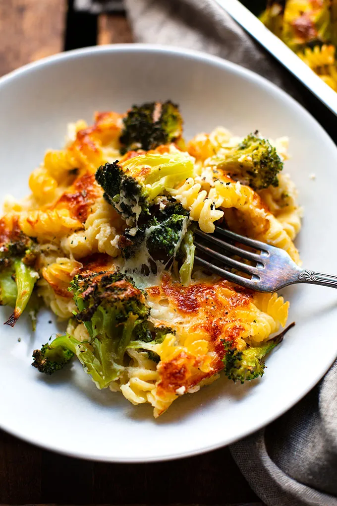 Fertiger Brokkoli-Nudelauflauf angerichtet auf einem weißen Teller mit einer Gabel. 