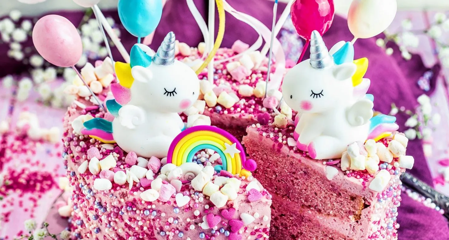 Fertiger Einhorn Geburtstagskuchen mit Dekorationen auf dem Tisch