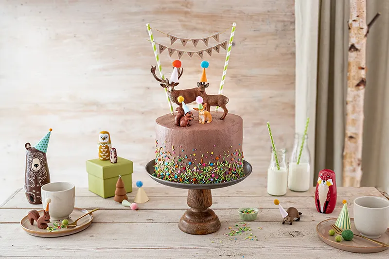 Fertiger Geburtstagskuchen Waldtiere mit Spielzeugfiguren, Partyhüten und bunter Wimpelkette