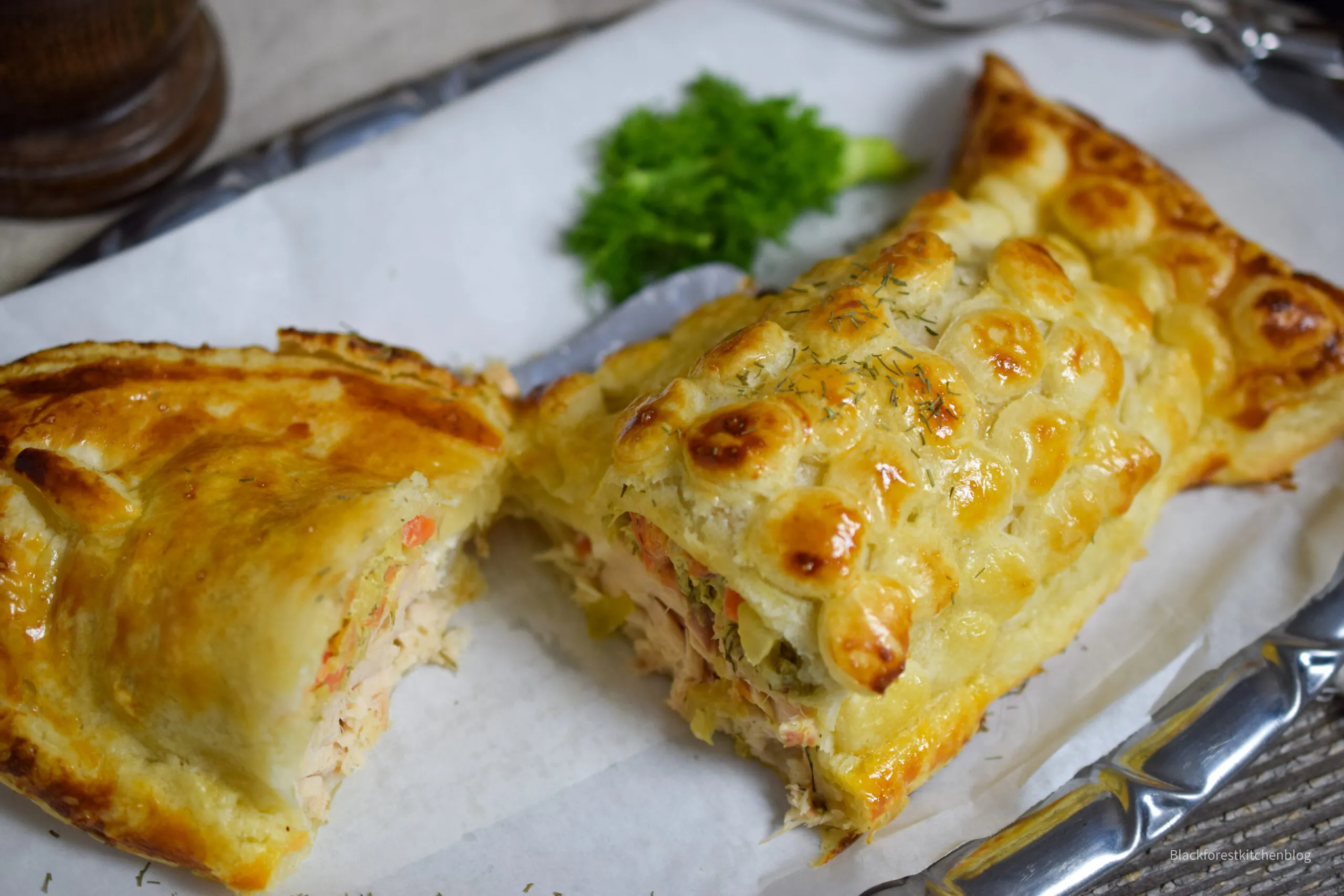 Fertiger Lachs im Blätterteig in Fischform, kunstvoll verziert auf einem Teller, perfekt gebacken und appetitlich angerichtet