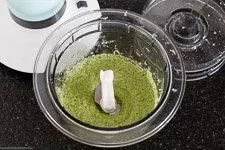 Fertiges Rucola Pesto in einer kleinen Schüssel, bereit zum Servieren, mit frischem Rucola und einem Löffel daneben.