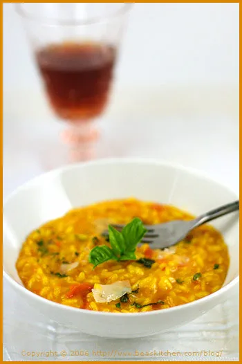 Fertiges Safran Risotto, ansprechend angerichtet mit Basilikumblättern und einem Löffel