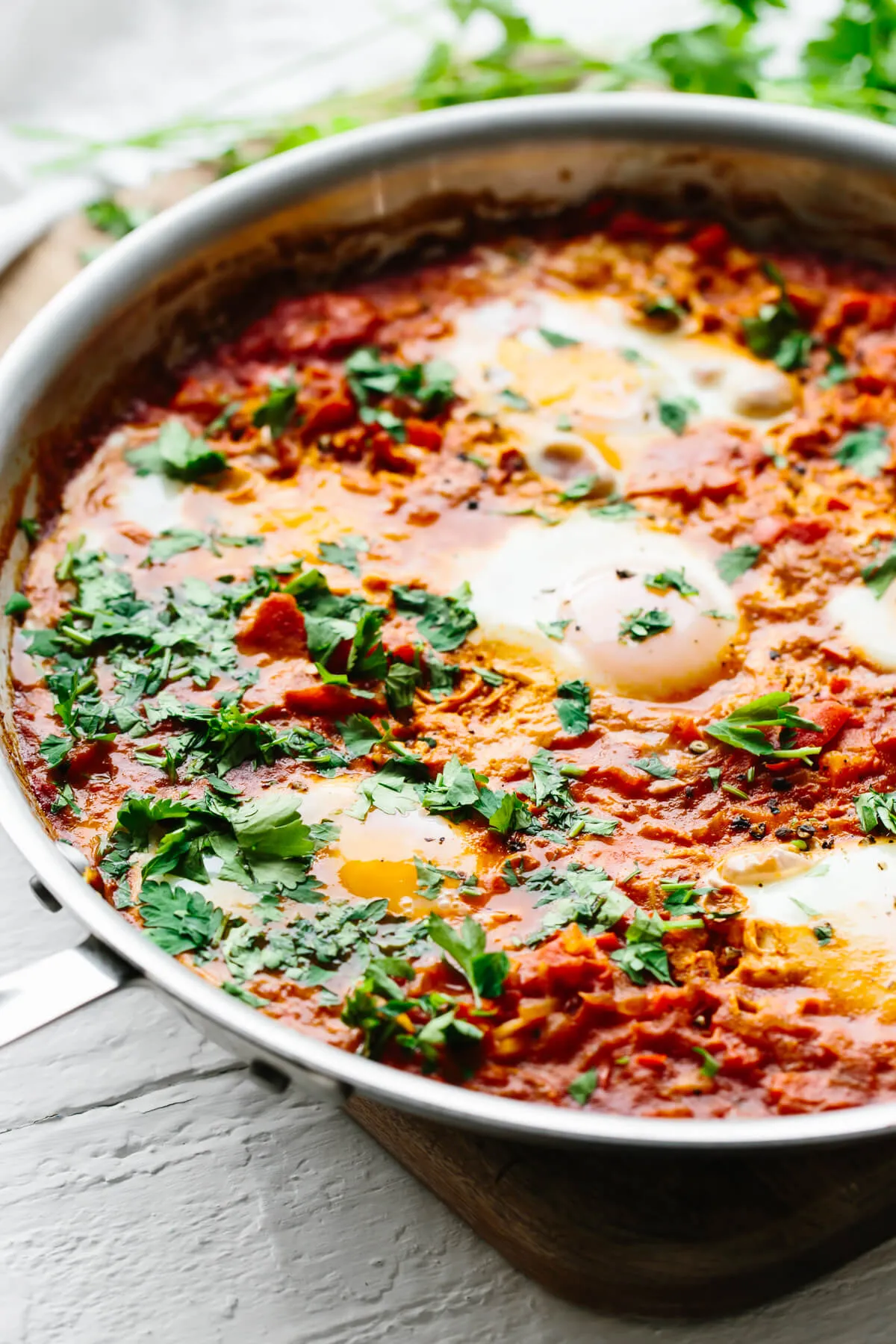 Fertiges Shakshuka-Gericht in einer Pfanne, bereit zum Servieren, garniert mit frischen Kräutern.