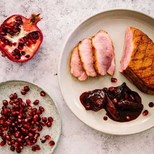 Festlich angerichtete Entenbrustscheiben mit Portweinzwiebeln und Granatapfelkernen