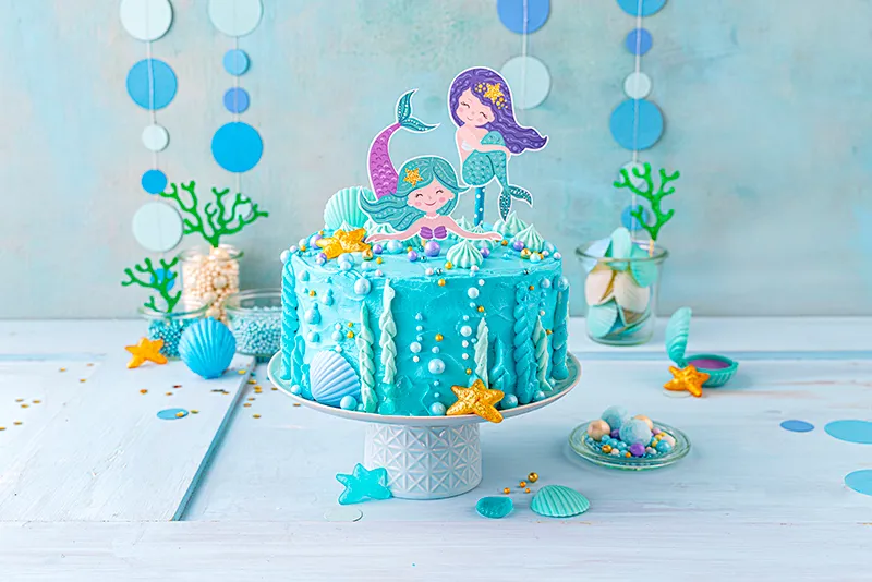 Festliche Meerjungfrauen-Torte mit glänzenden Dekorperlen als letzte Verzierung, perfekt für den Kindergeburtstag