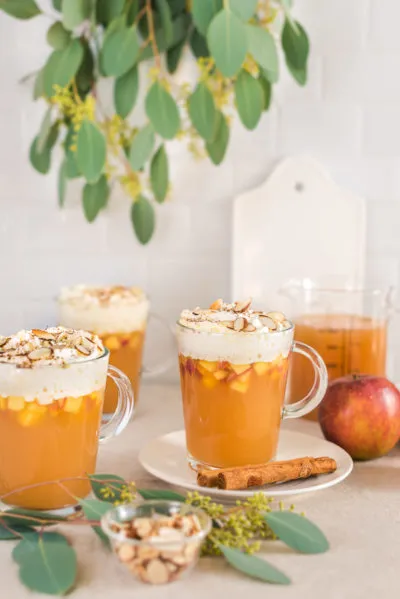 Festlicher Bratapfelpunsch mit Vanille-Zimt-Sahne und gerösteten Mandeln, perfekt für den Herbst.